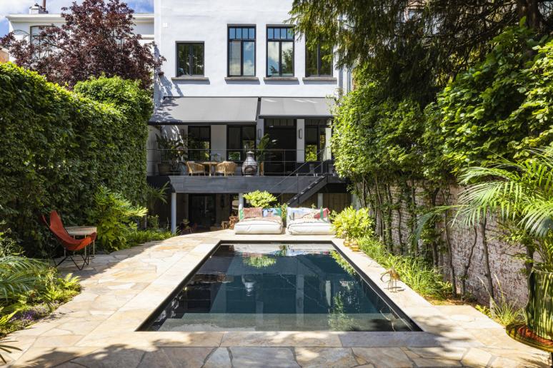 Zwembad in tuin met zicht op een wit huis